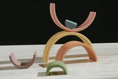 Several colorful, arched wooden blocks are stacked and balanced on a white marble surface, representing the unique patterns of autism spectrum disorders.