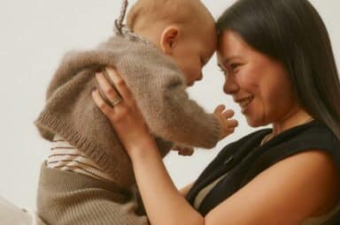 Smiling mother and infant touching foreheads, demonstrating how to build a secure attachment bond.