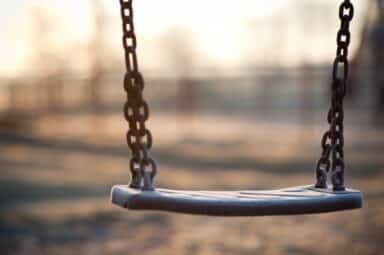Empty playground swing at sunset, representing the isolation of child abuse and neglect.