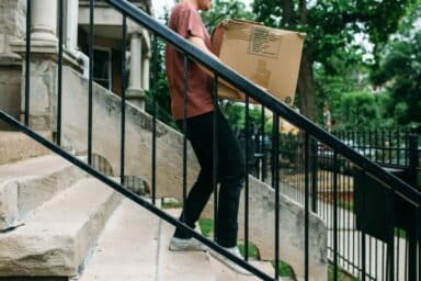 A man carefully descends stairs while carrying a large box, demonstrating how to deal with a breakup or divorce.
