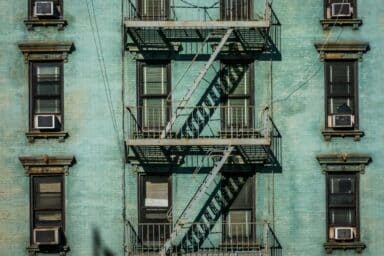 Exterior view of a teal apartment building with metal fire escapes, symbolizing where domestic violence and abuse can occur.