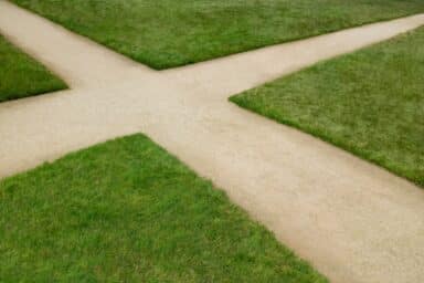 Two dirt paths through a grass field meet at a crossroad, representing the intersection of addiction and mental health.