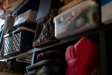 Shelves filled with various items, including a black plastic bin, a quilted bag, and a clear storage container.