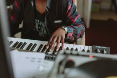 A person wearing a plaid shirt and a silver watch plays a electronic keyboard, representing how to improve your memory.