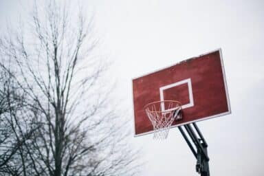 A weathered red basketball backboard with a white rim stands against a grey, overcast sky, representing a parent's guide to teen depression.
