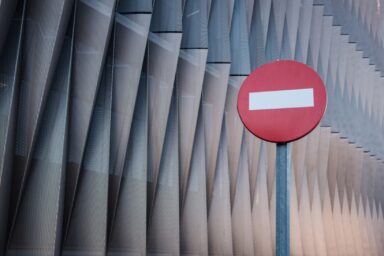 A red and white circular "No Entry" sign stands against a backdrop of sharp, angular metal slats, representing phobias and irrational fears.