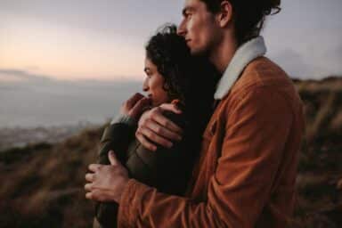 A couple embraces on a hilltop at sunset, embodying .