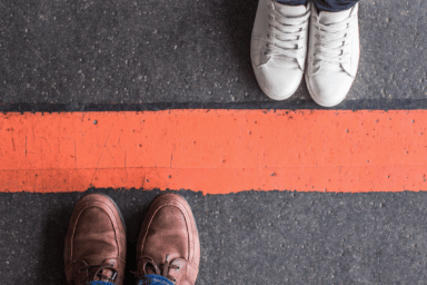 Two people stand either side of a red line, symbolizing setting boundaries in relationships